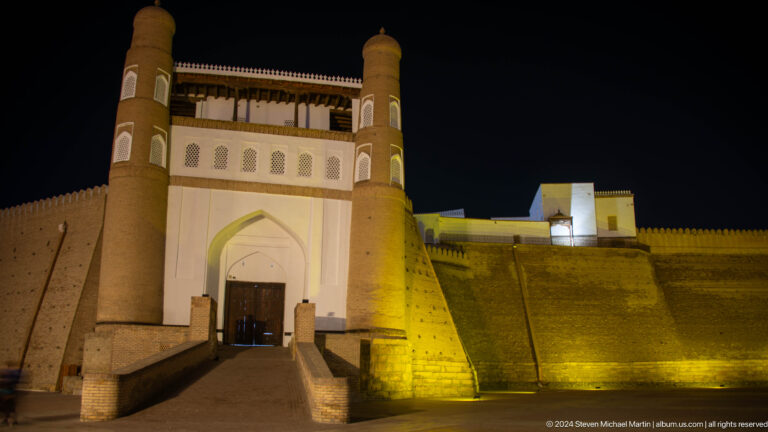Night view of the Ark of Bukhara entrance gate above a ramp.