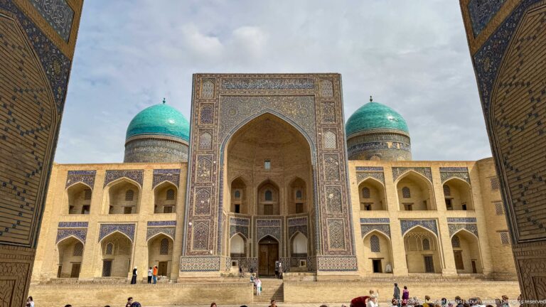 Mir-i-Arab Madrasa framed through an arch, with turquoise domes.