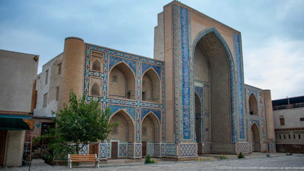 Large blue-tiled madrasa facade at angle.
