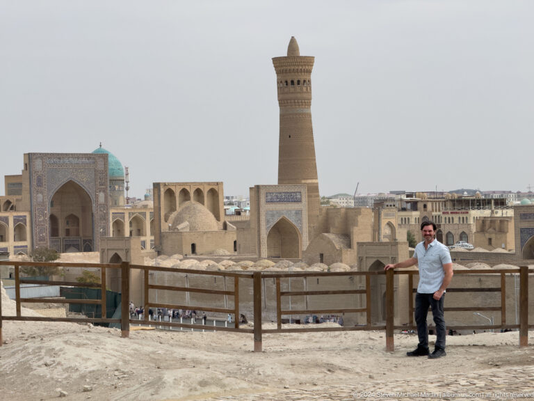 Man standing at a railing before the Kalyan Minaret and Po-i-Kalyan complex.