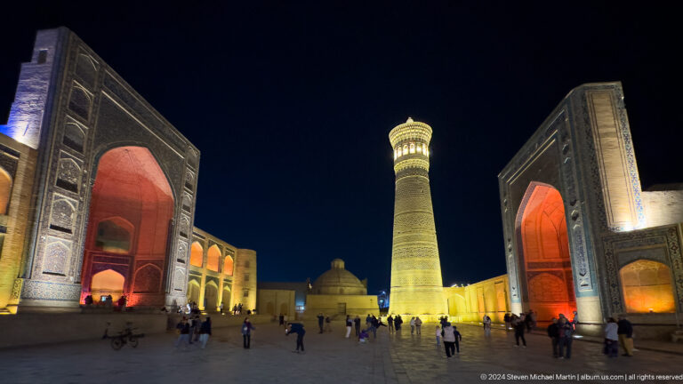 Kalyan Minaret centered between red-lit portals in Po-i-Kalyan square at night.