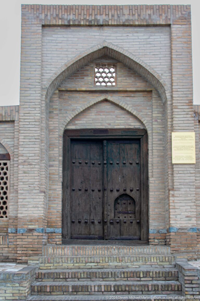 Dark wooden arched doorway beneath pointed recess.