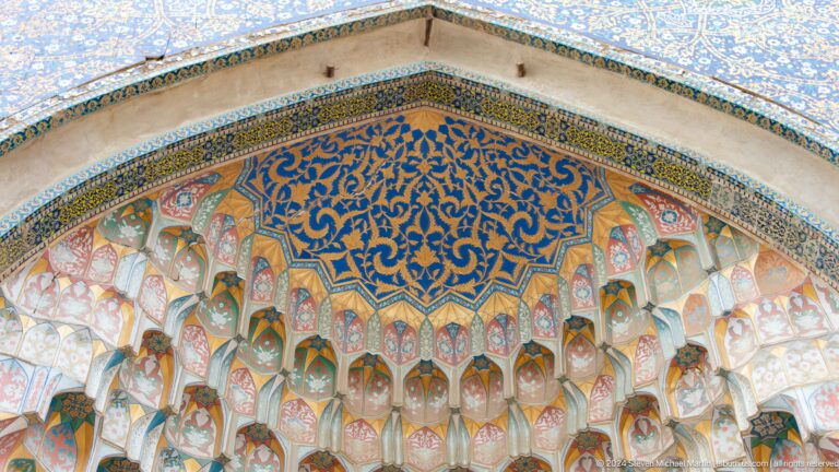 Painted muqarnas beneath blue arabesque panel.