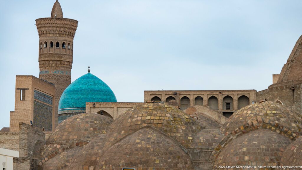 Turquoise dome and minaret beyond brick roofs.