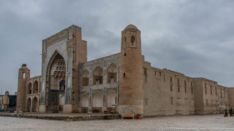 Monumental mosque facade and minaret under cloudy sky.