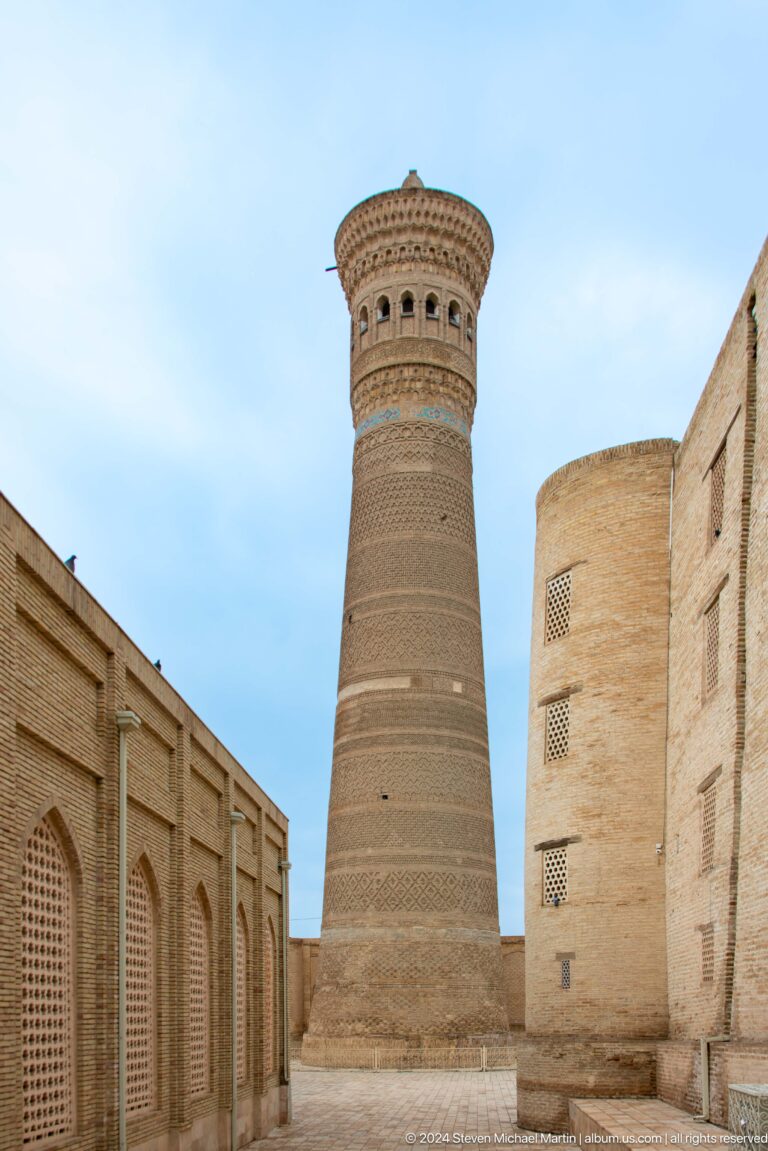 Kalyan Minaret rising between brick buildings.