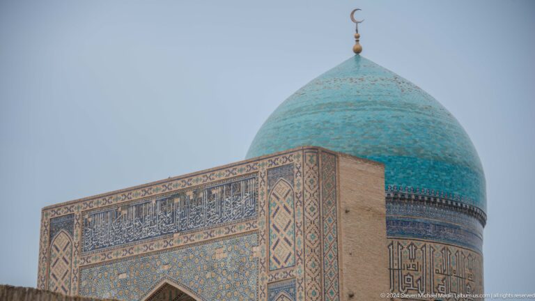 Turquoise dome behind patterned parapet.