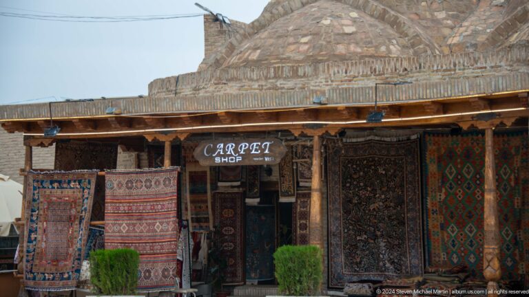 Carpet shop beneath carved wooden canopy.