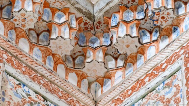 Close view of orange and blue muqarnas cells.