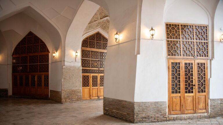 White vaulted interior with carved wooden doors.