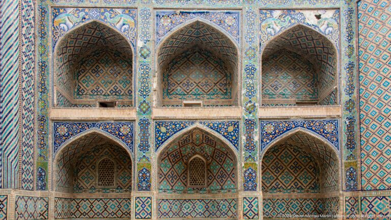 Six tiled arched bays across madrasa facade.