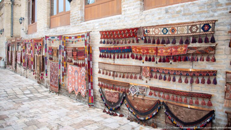 Rows of embroidered textiles at market.