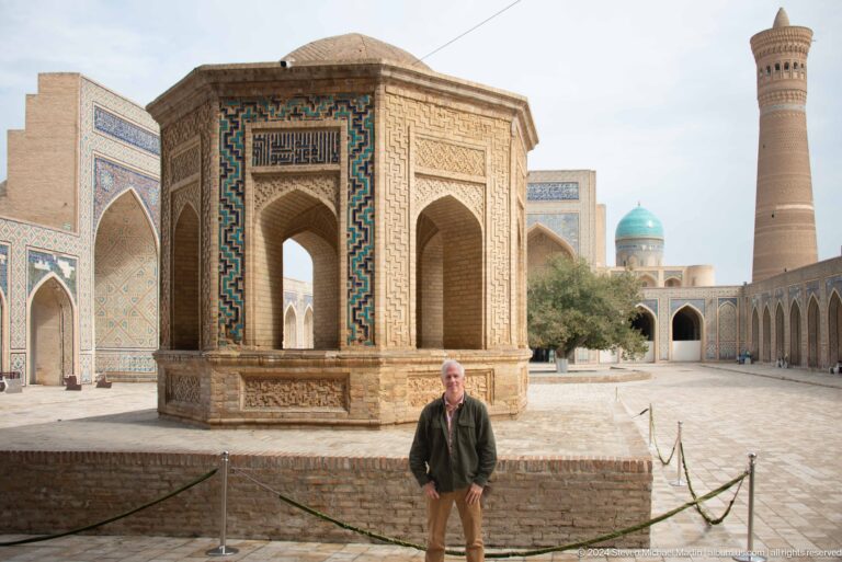 Visitor standing beside pavilion in mosque courtyard.
