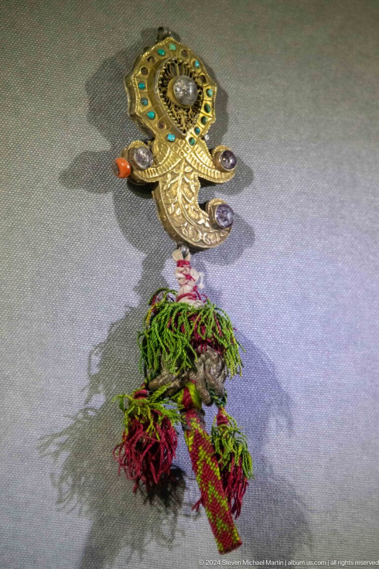 Metal ornament with tassels and green fibers.