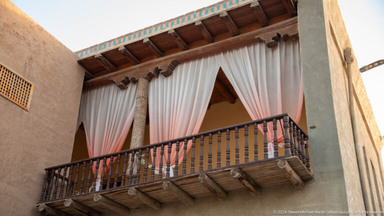 Balcony with white curtains on historic facade.