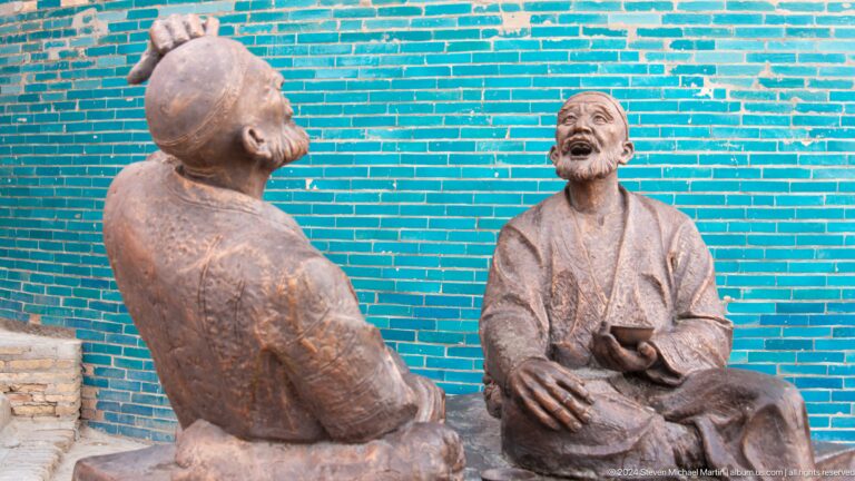 Bronze figures in animated conversation against turquoise wall.