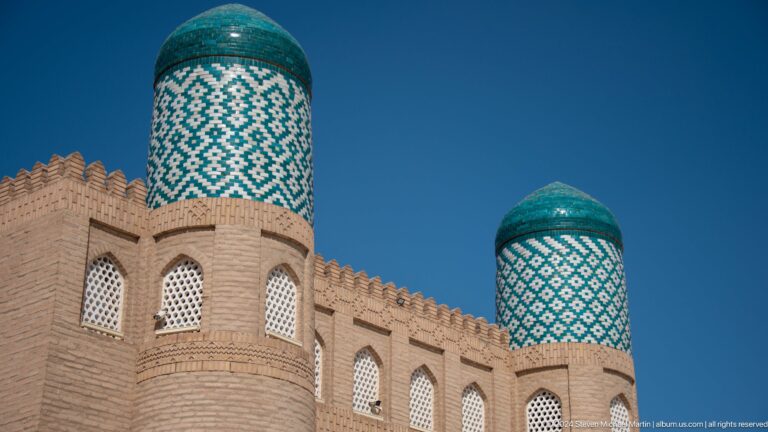 Fortified wall with turquoise-capped corner towers.