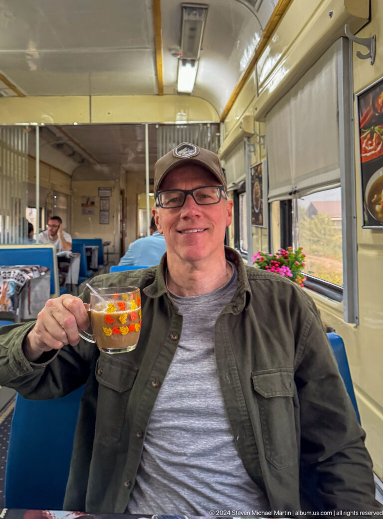 Smiling traveler raising a glass of tea on train.