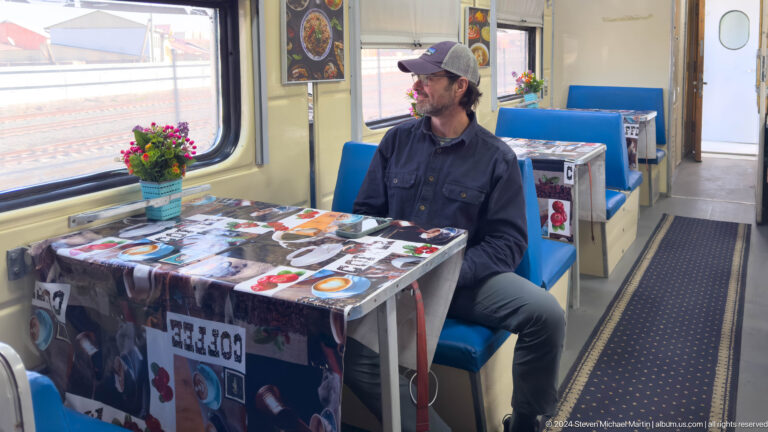 Traveler seated at table in railway dining car.