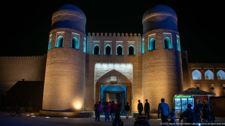 Twin-towered ata darvaza gate illuminated blue.