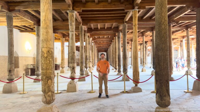Juma mosque columns with visitor in orange shirt.