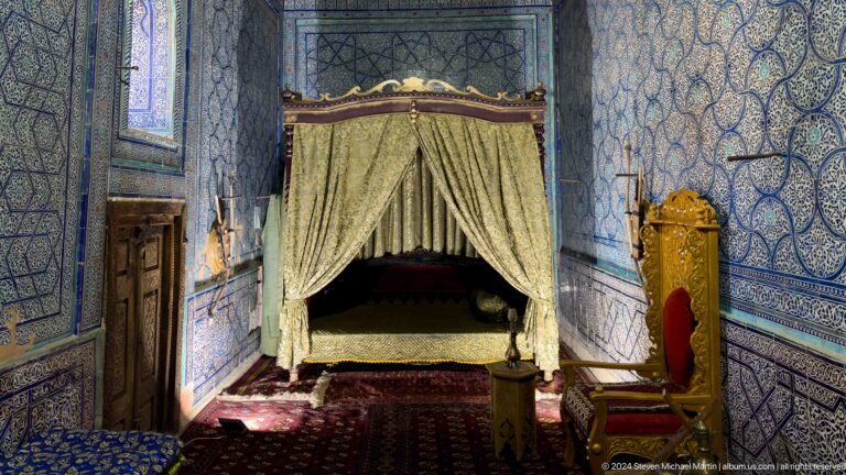 Canopied bed in decorated palace chamber.