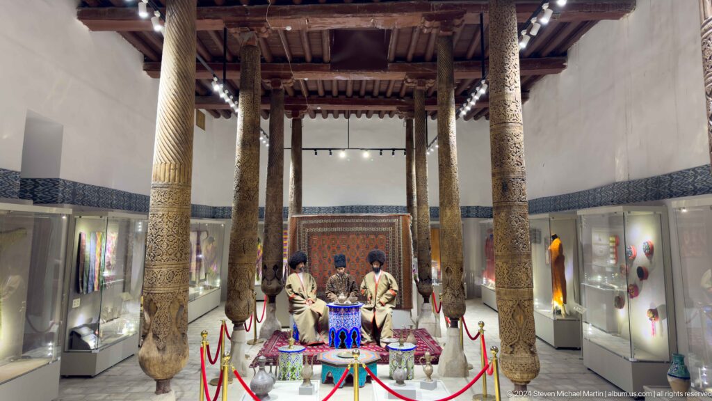 Museum display staged among carved wooden columns.