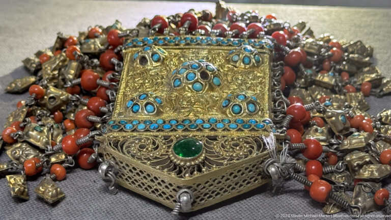Square filigree ornament set with turquoise and green stones.