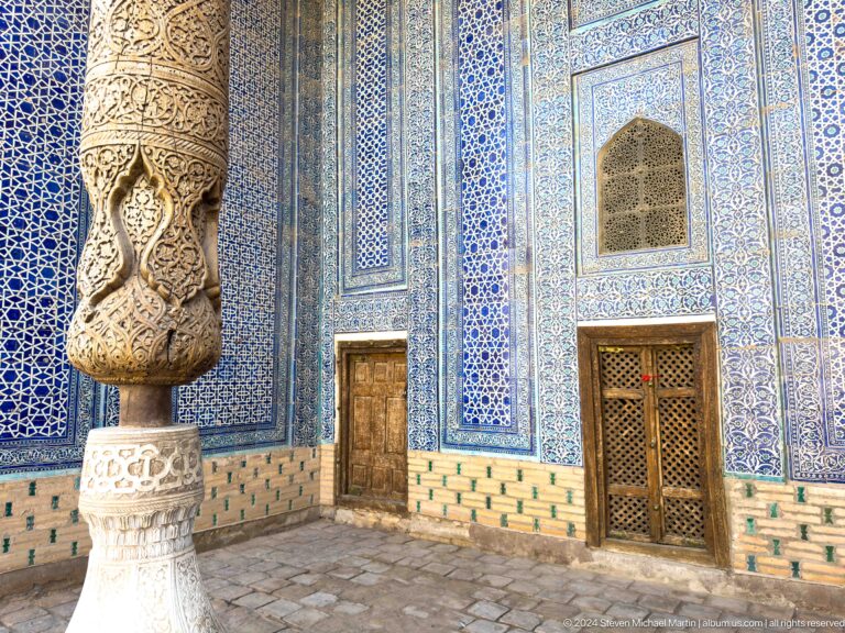 Carved stone or wooden column base beside tiled doorway.