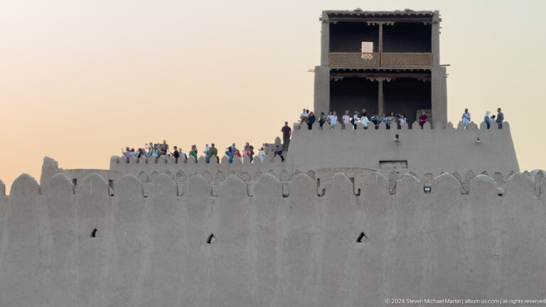 Crowd silhouetted along fortress wall and watch platform.