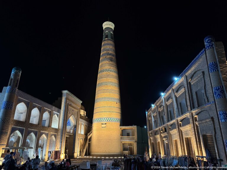 Islam khoja minaret and illuminated madrasa facades.