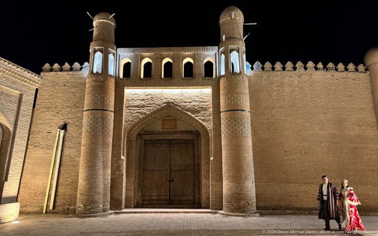 Monumental gate with flanking towers at night.