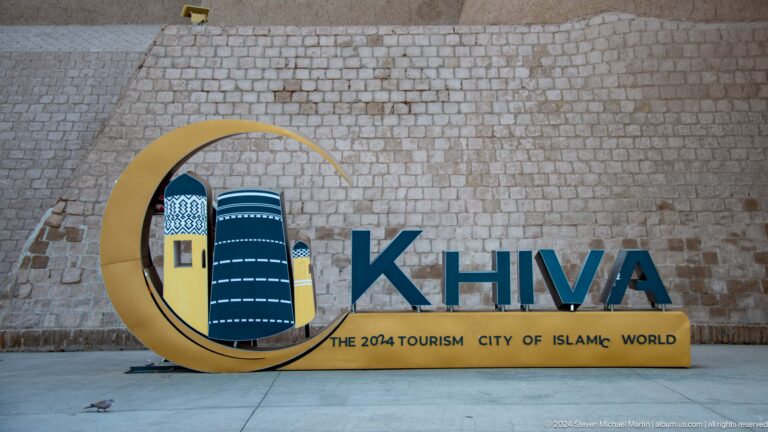 Khiva tourism sign on pale stone wall.