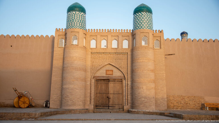 Sunlit historic gate with turquoise-capped towers.