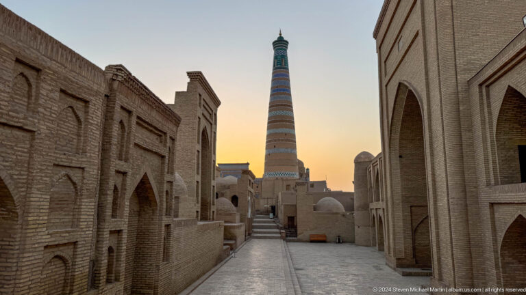 Narrow street leading toward islam khoja minaret at sunset.