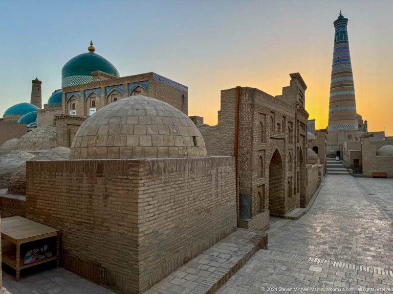 Domed brick tomb beside lane at sunset.