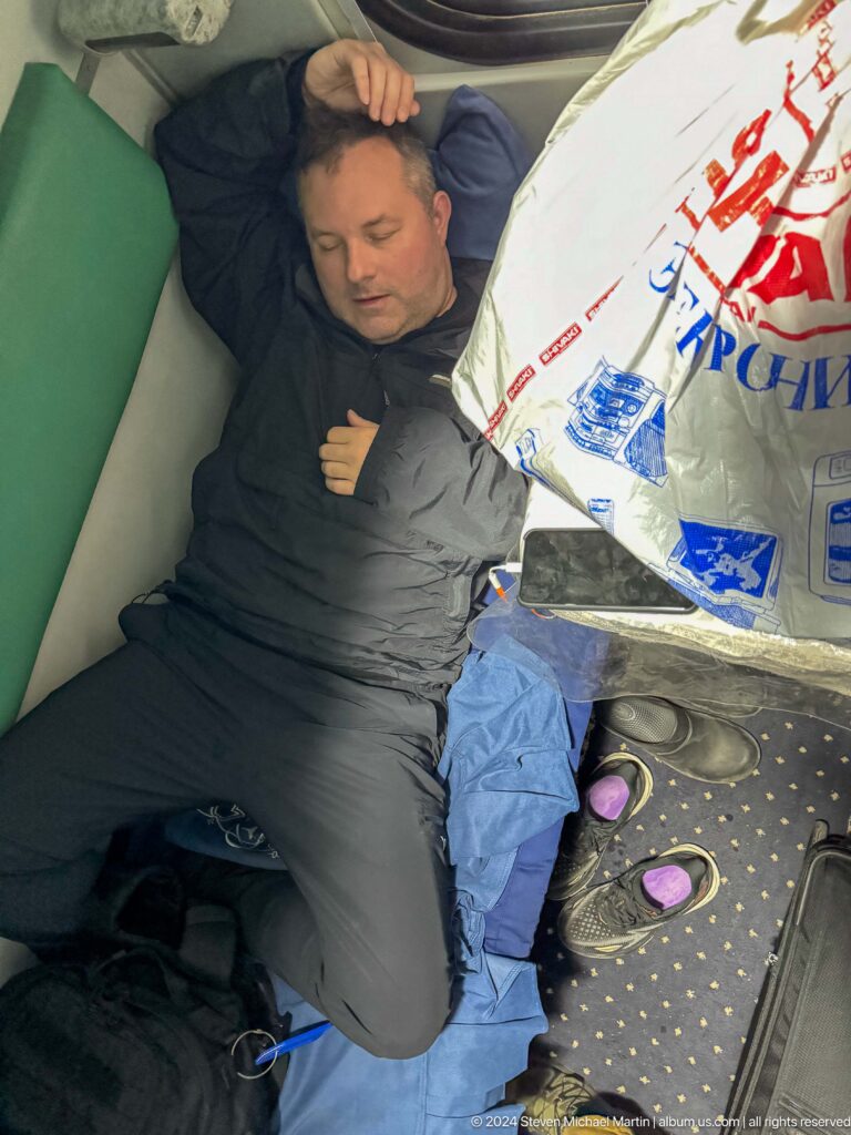 Traveler reclining beside shopping bags on a train seat.