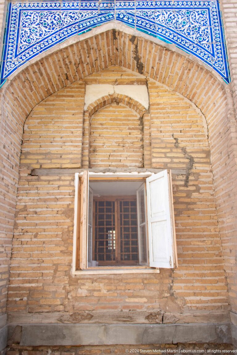 Small white-framed window in weathered brick wall.