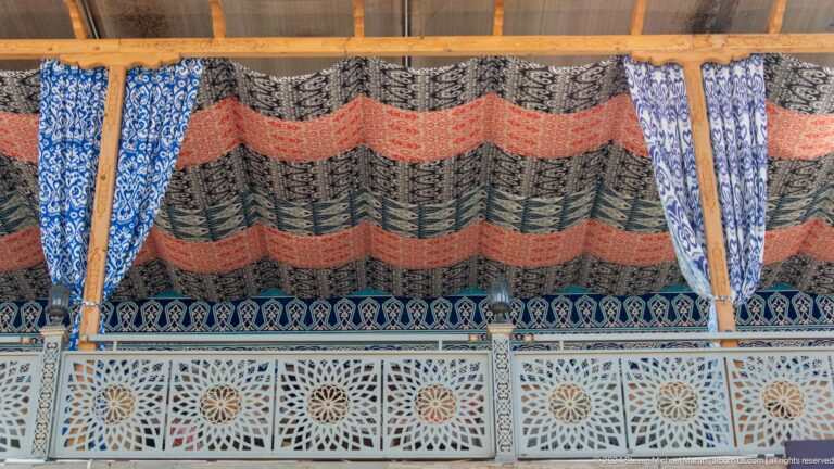 Striped woven textile hanging above carved wooden lattice.