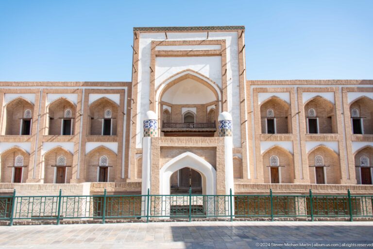 Symmetrical madrasa facade seen across a railing.