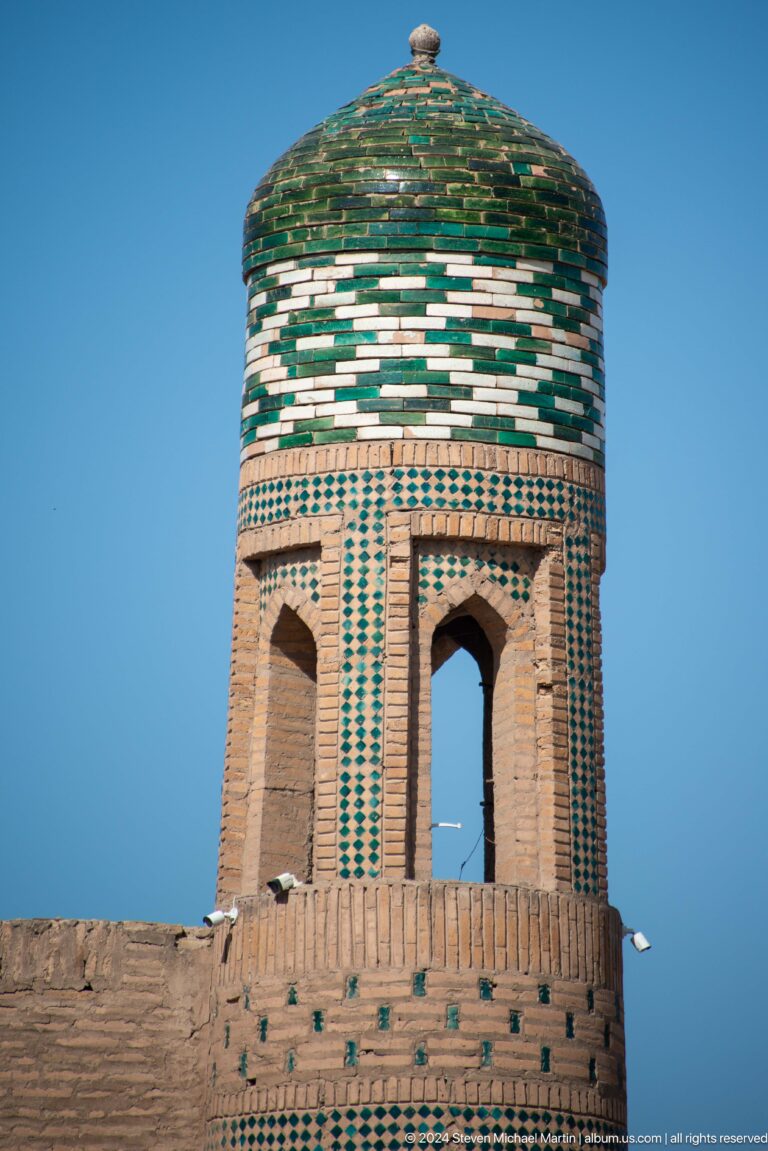 Tile-banded brick minaret detail with pointed openings.