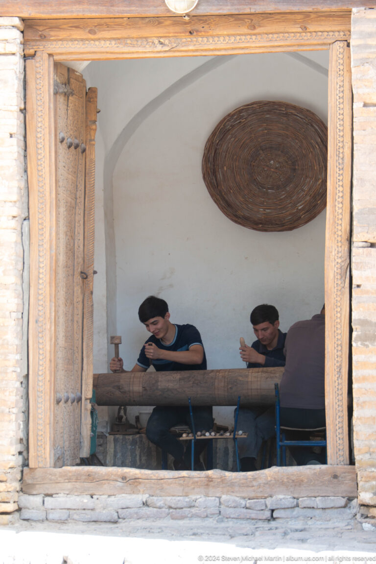 Two men seated in a shaded doorway.