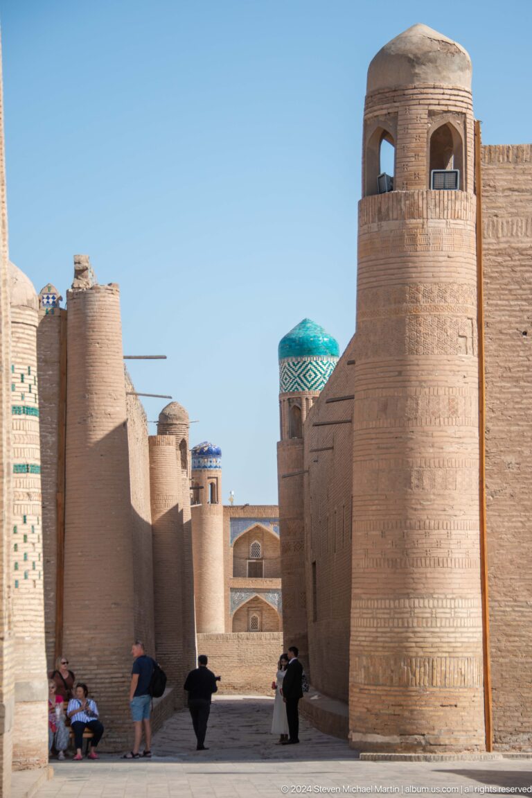 Narrow lane framed by mud-brick walls and minarets.