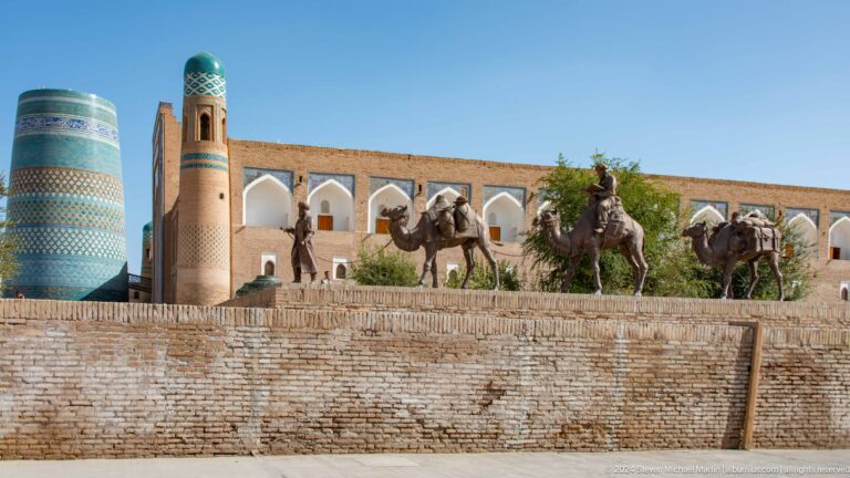 Camels walking along wall beneath kalta minor.