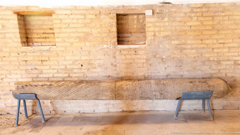 Simple brick wall with benches and small opening.