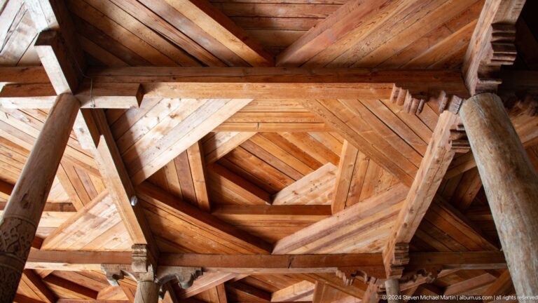 Geometric timber ceiling viewed upward.