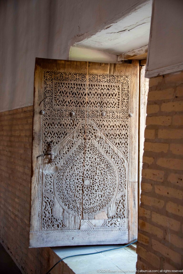 Intricately carved wooden door with pointed central panel.