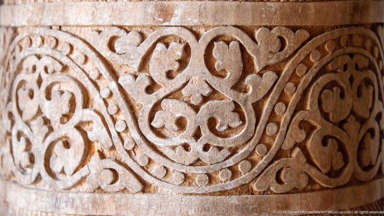 Close-up of carved vegetal scrollwork in wood.
