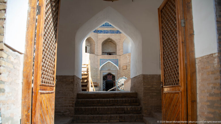 Stairway framed by pointed arches and wooden doors.