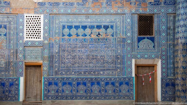 Blue-tiled palace wall with doors and lattice windows.